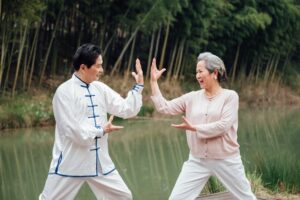 Asian senior couple practicing tai chi outside by the river